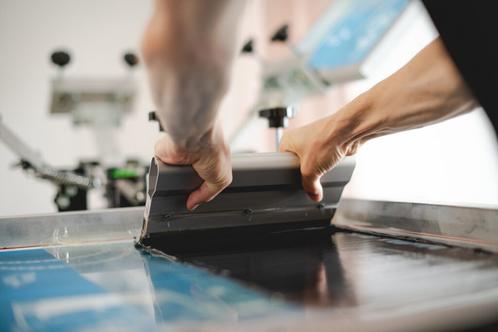 A person performing screen printing on a shirt.