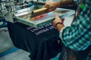 A person screen printing a black t-shirt in El Paso.